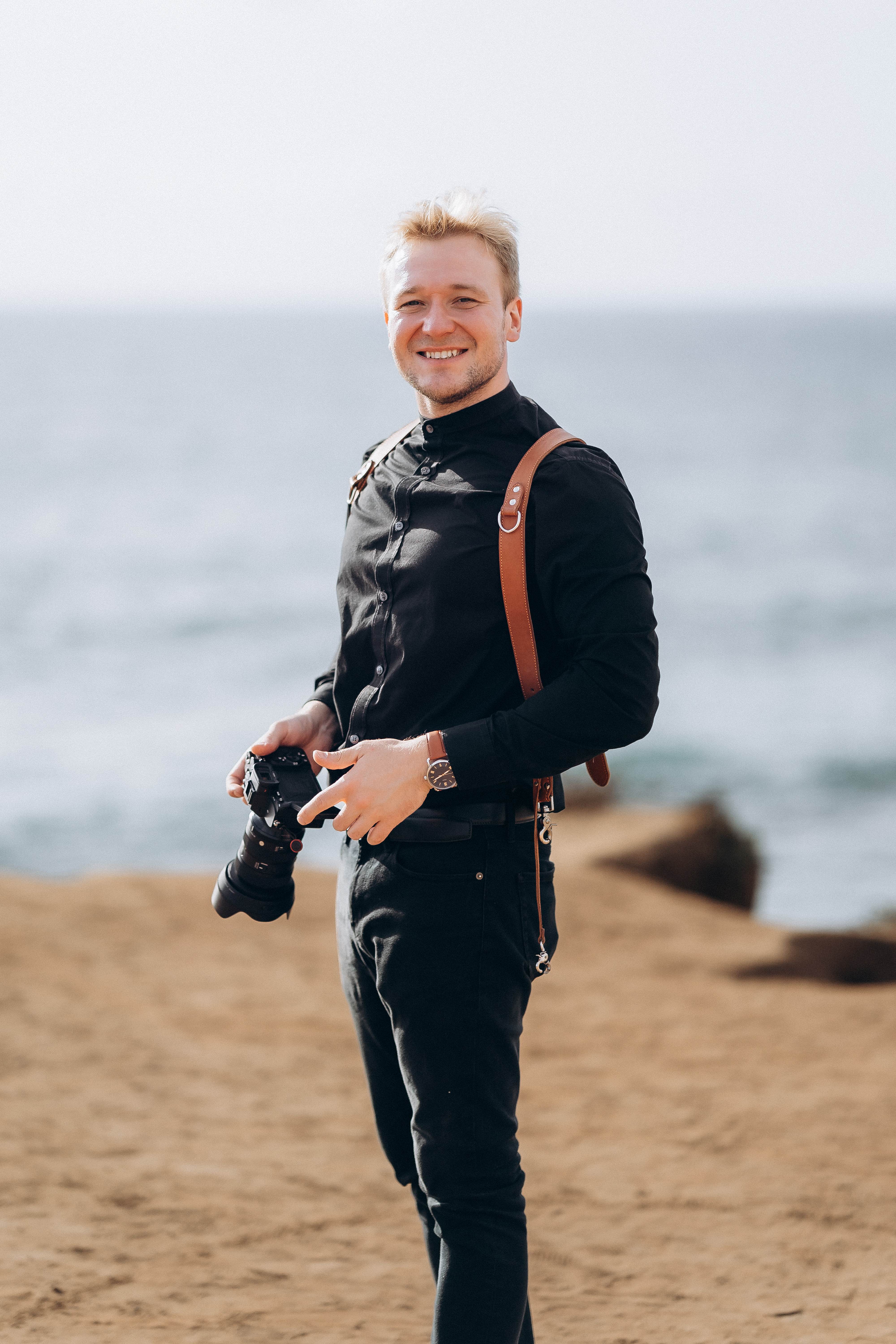 Francis, photographer, on the beach with camera and leather harness