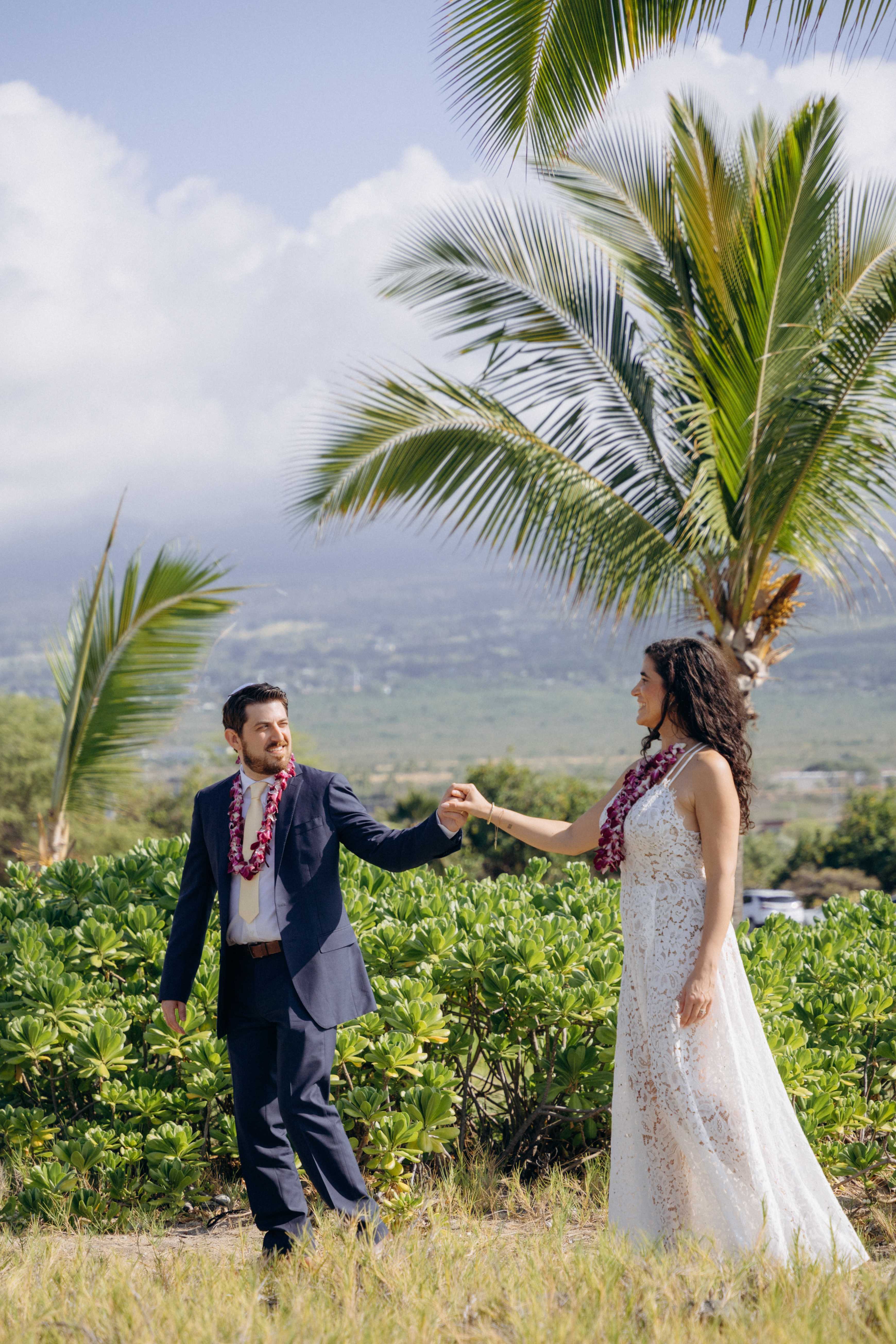 Couple holding hands in tropical greenery with palm trees